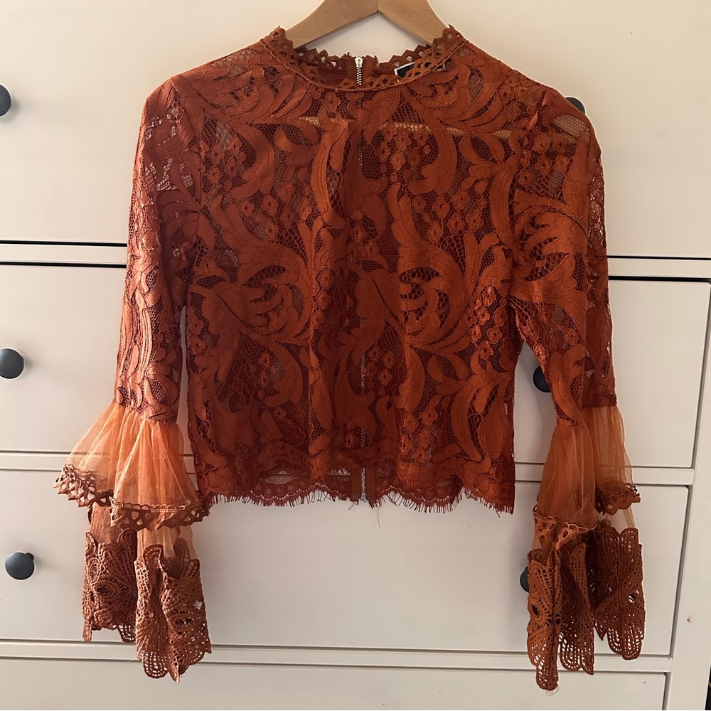 Beautiful rust colored lace top, zip up back, slight bell sleeves.